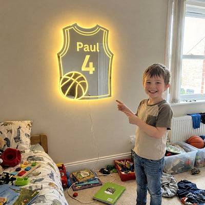 A boy proudly points at his glowing basketball jersey mirror